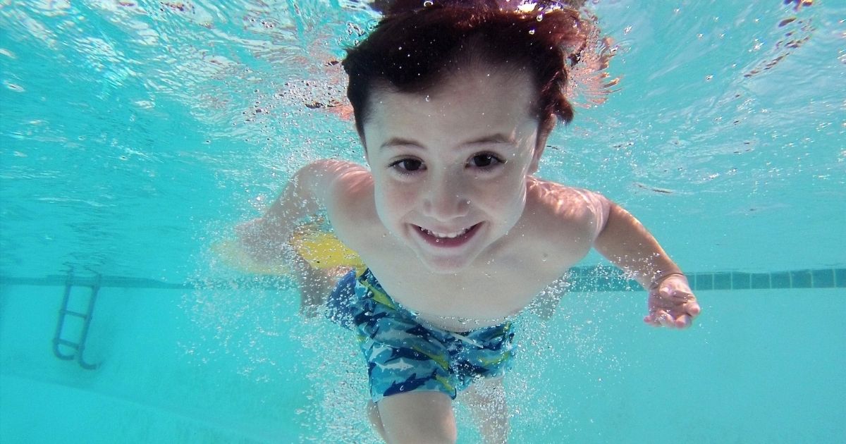 Criança autista sorrindo e brincando com brinquedos na piscina